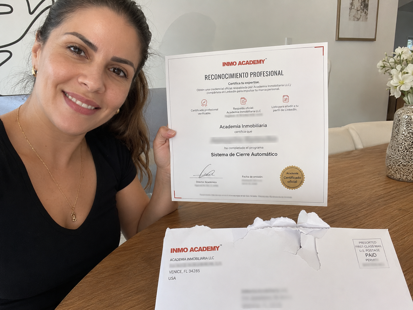 Alumna de INMO ACADEMY sosteniendo su certificado físico junto al sobre de envío